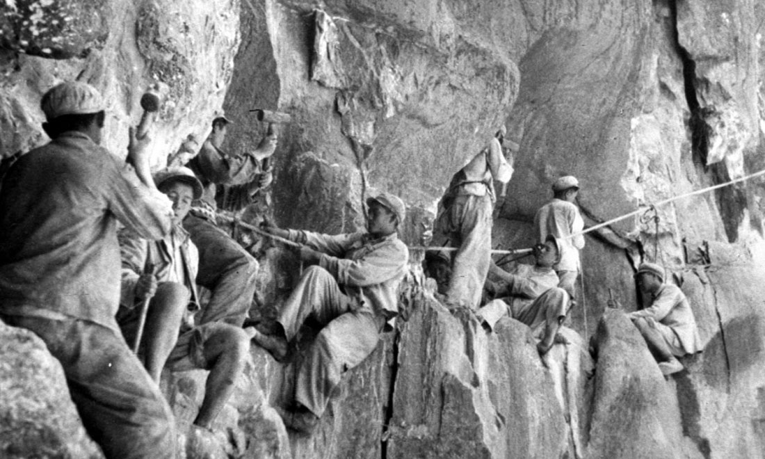 1954年，修筑康藏公路的解放軍戰(zhàn)士們在怒江兩岸的懸崖陡壁上辟山筑路。新華社稿 李萬春、張加里攝